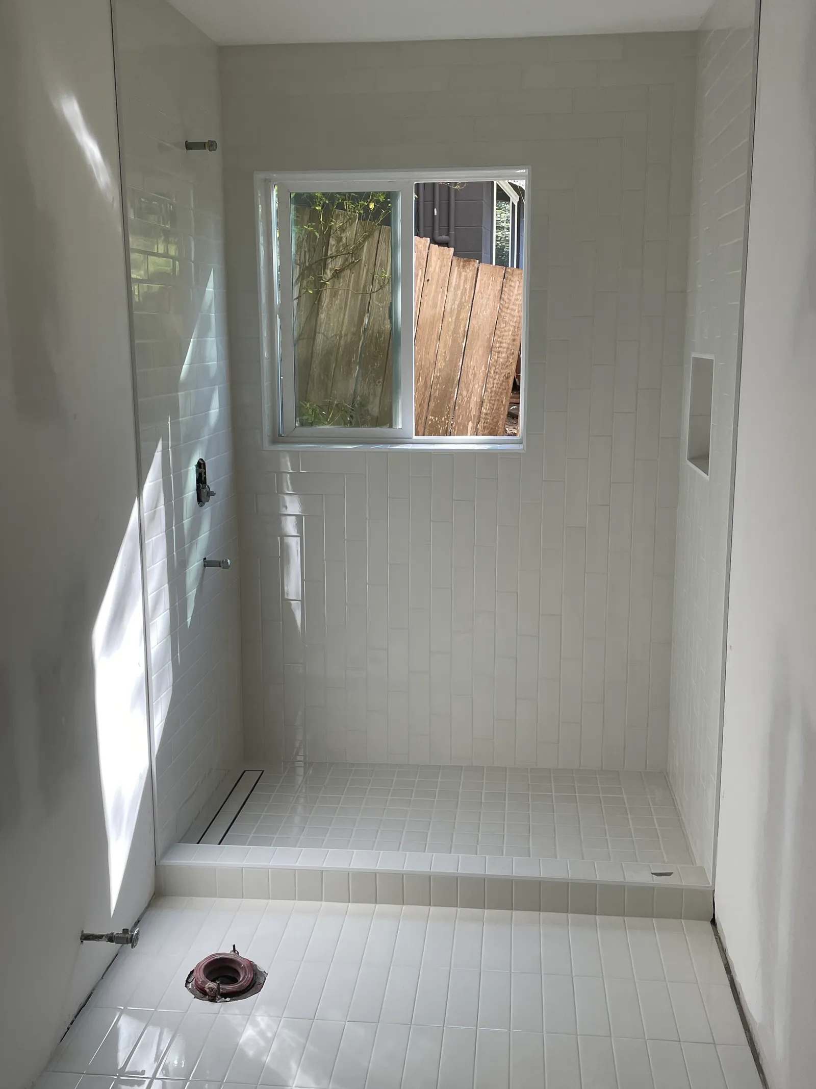Tiled shower with window, white subway tile walls, and shower floor