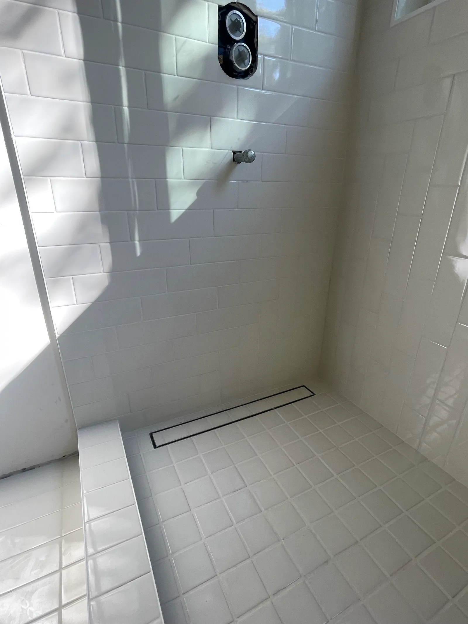 Bathroom tub surround with white tile and natural light from window