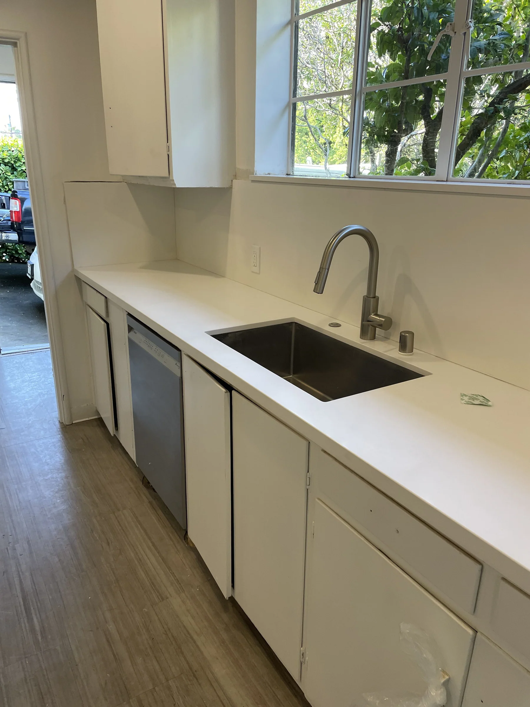 Finished Berkeley galley kitchen with white quartz countertops, undermount stainless sink, single-handle pull-down faucet, and casement window over the sink