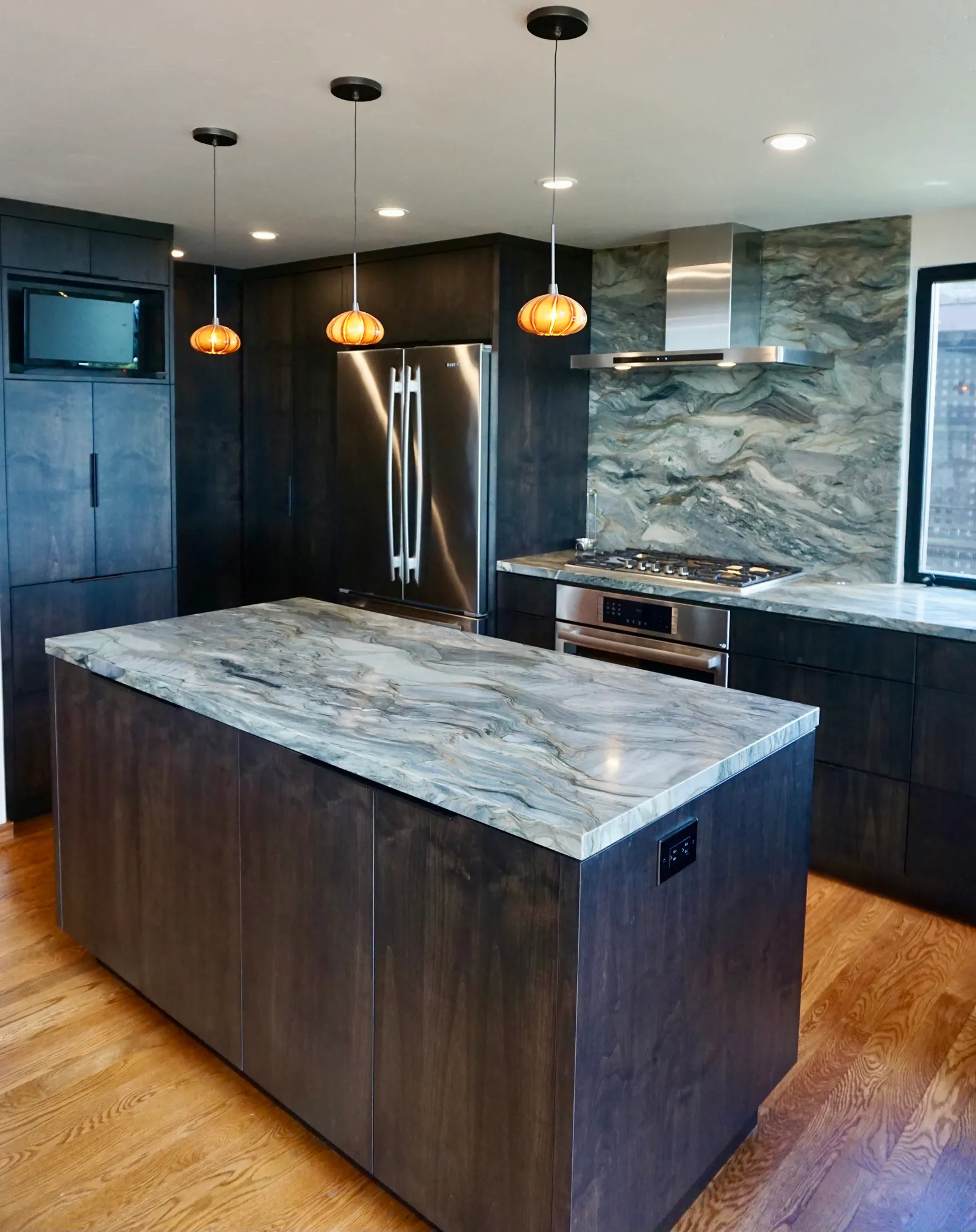 Veined marble kitchen island with pendant lights and hardwood flooring