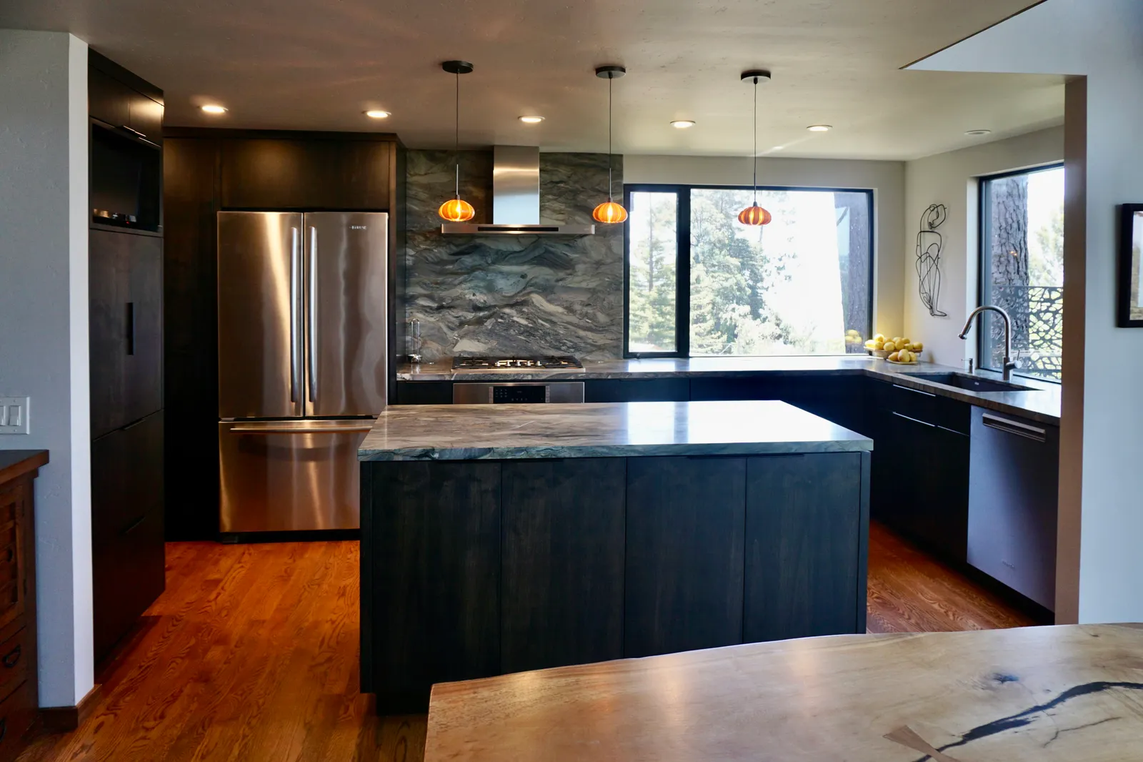 Modern kitchen with dramatic marble island and full-height backsplash, pendant lights