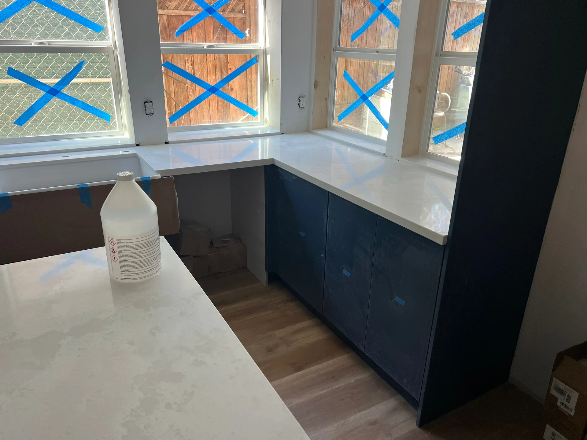 Bay window corner of navy cabinet kitchen with quartz countertop and hardwood flooring