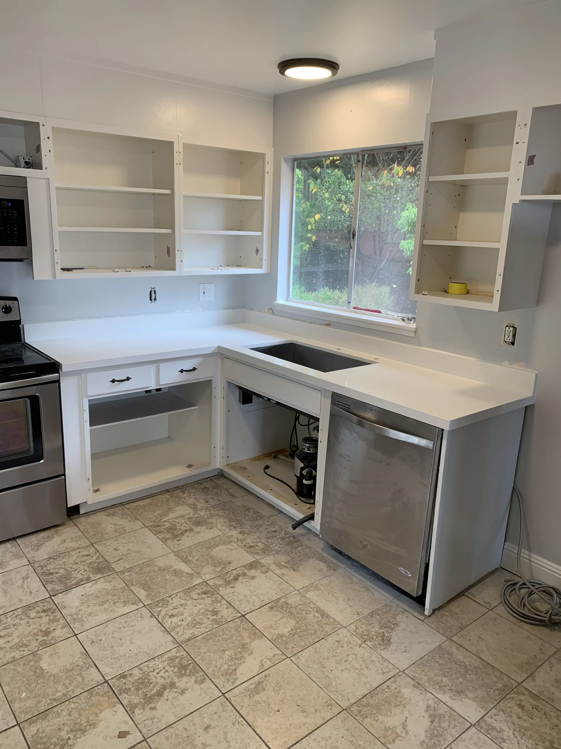 Berkeley kitchen mid-project with white quartz countertop installed and cabinet doors off for prep, stainless range and dishwasher