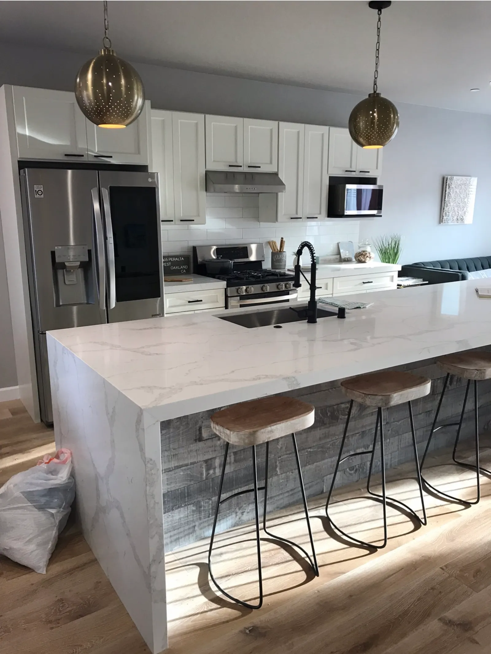 Kitchen with quartz waterfall island, pendant lights, bar stools, and hardwood floors