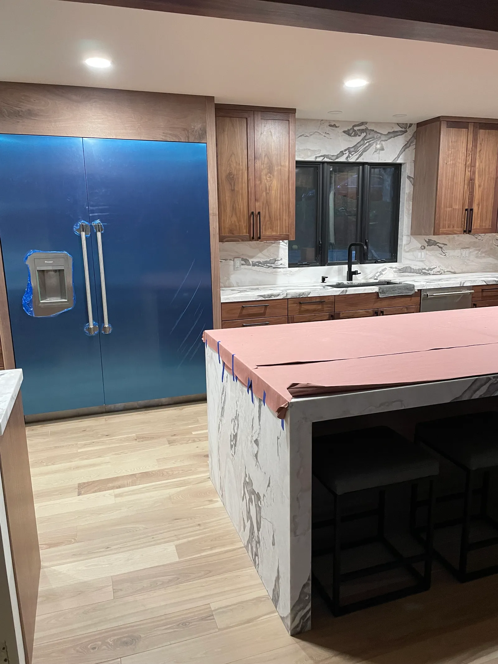 Modern kitchen with walnut cabinets, marble countertops, and blue range