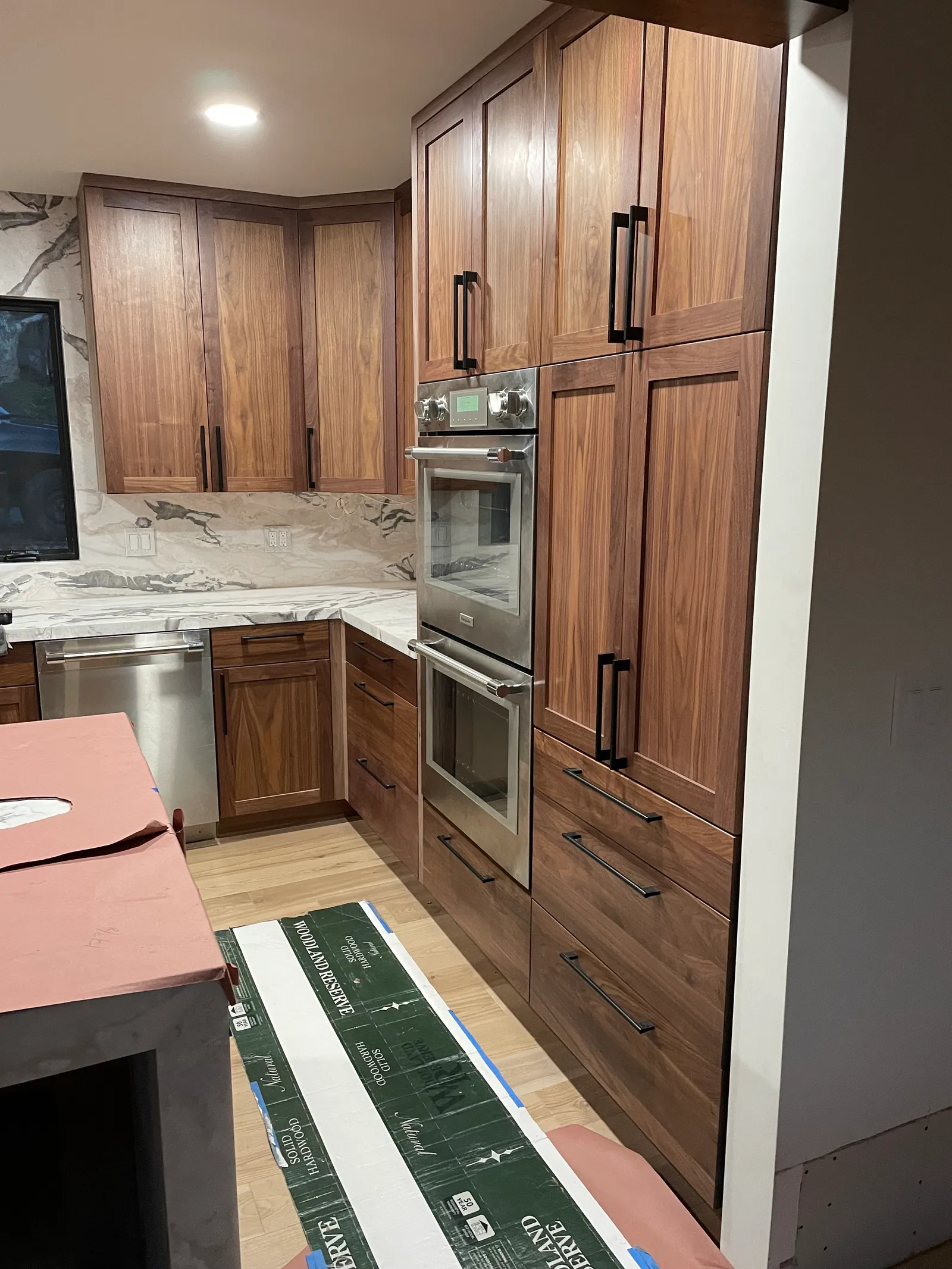 Kitchen remodel in progress — walnut cabinets installed with marble countertops