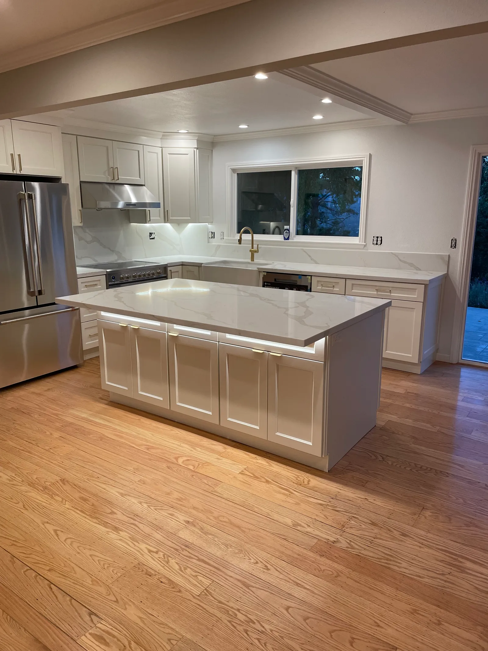 Complete white shaker kitchen remodel with marble-look quartz and hardwood floors