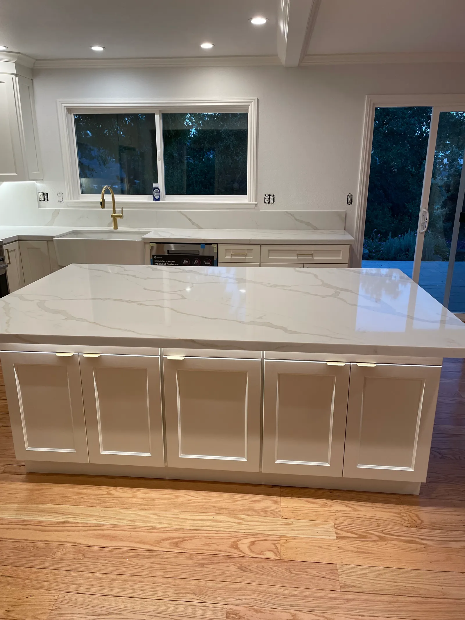 Full kitchen view with white shaker cabinets, quartz counters, and oak hardwood floors